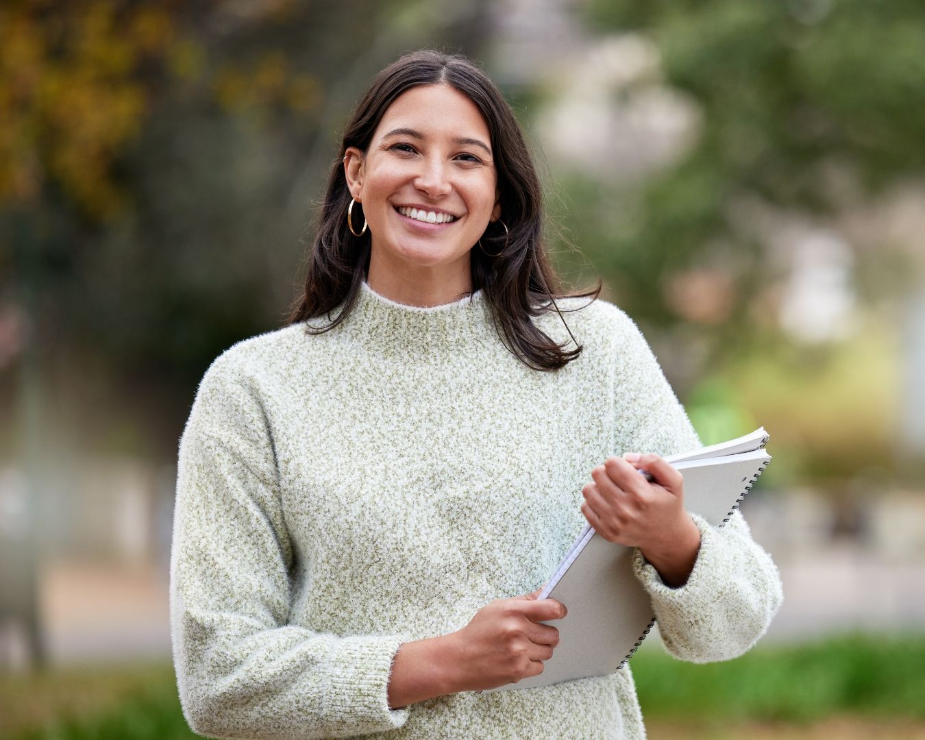 Brown haired woman smiling while holding a notepad