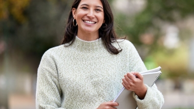 Brown haired woman smiling while holding a notepad